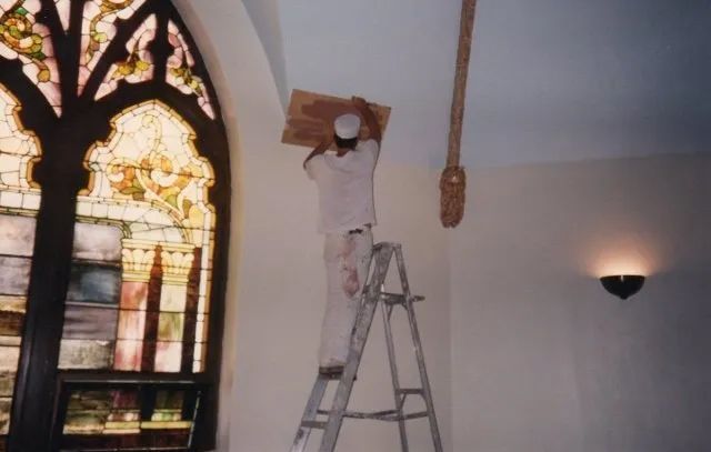 A man on a ladder in front of a stained glass window