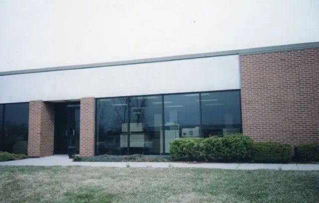 A large brick building with a lot of windows and bushes in front of it.