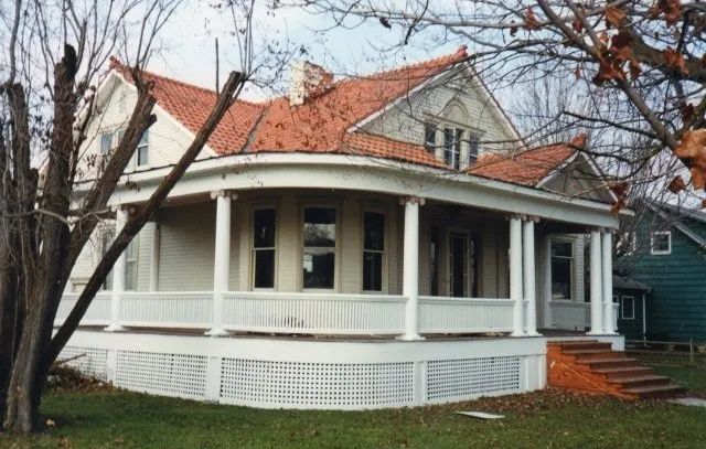 A white house with a red roof and a large porch