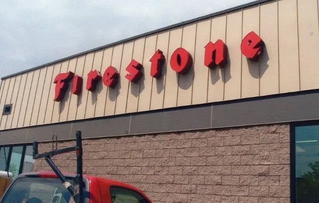 A red truck is parked in front of a firestone store