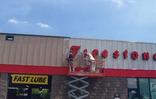 A man is painting the front of a tire store