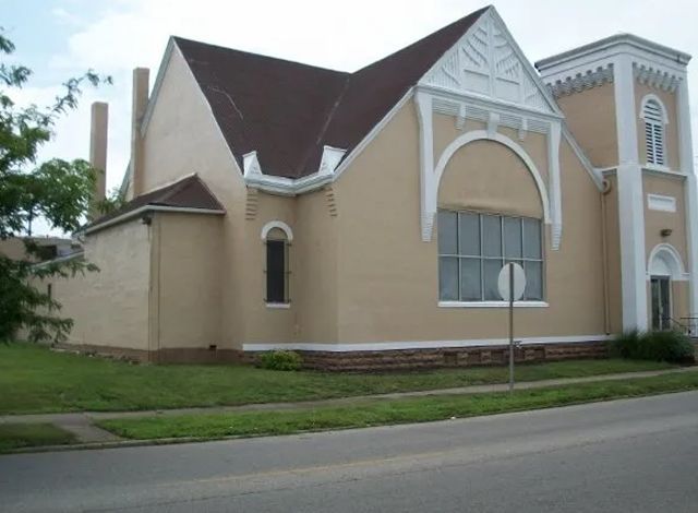 A church with a brown roof and a white sign in front of it