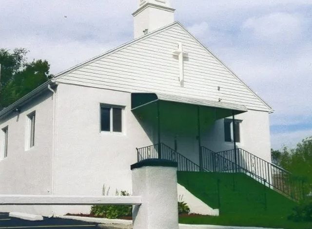 A white church with a cross on the top of it