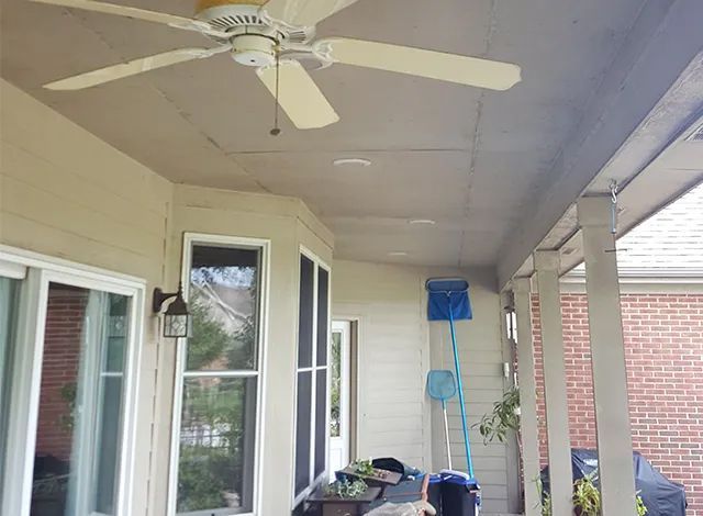 A ceiling fan is hanging from the ceiling of a porch.