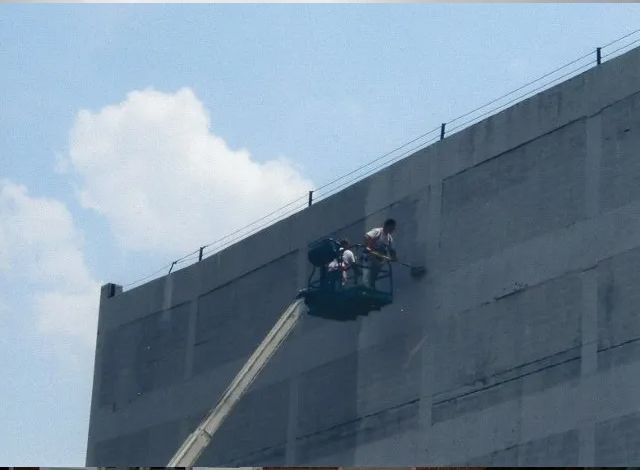 A group of people are working on the side of a building.