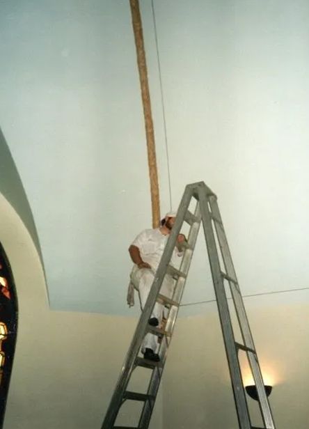 A man is standing on a ladder hanging from the ceiling