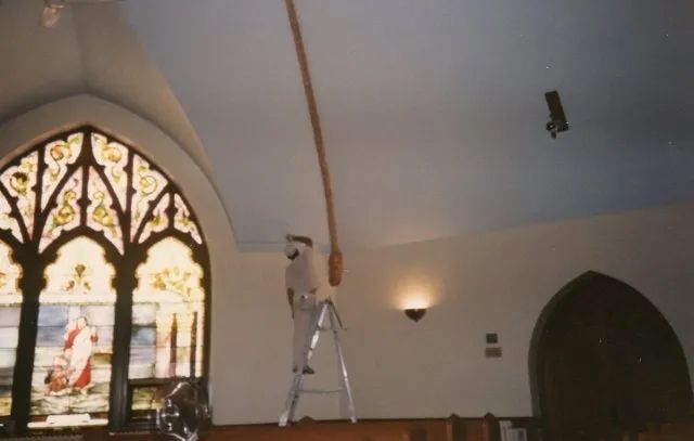 A man on a ladder in front of a stained glass window