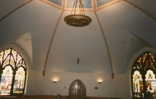 A church with stained glass windows and a chandelier hanging from the ceiling