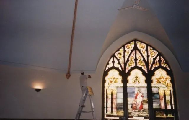 A man on a ladder in front of a stained glass window