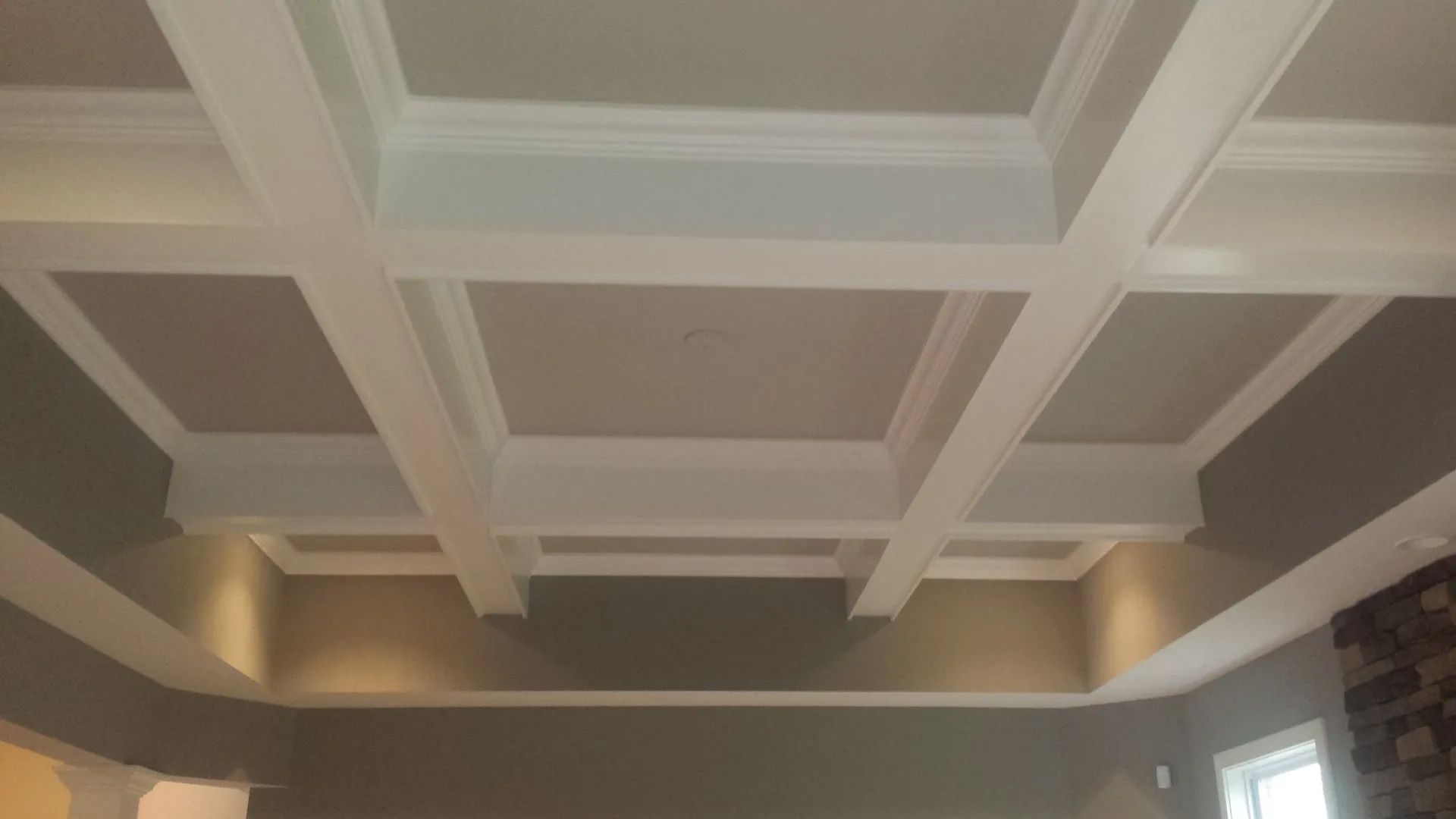 A living room with a coffered ceiling and a fireplace.