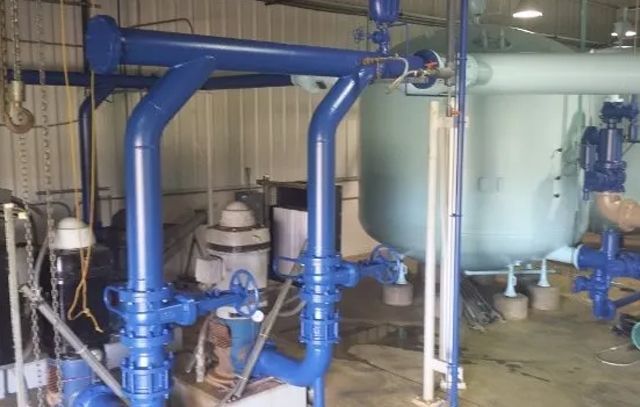 A room filled with blue pipes and a large tank