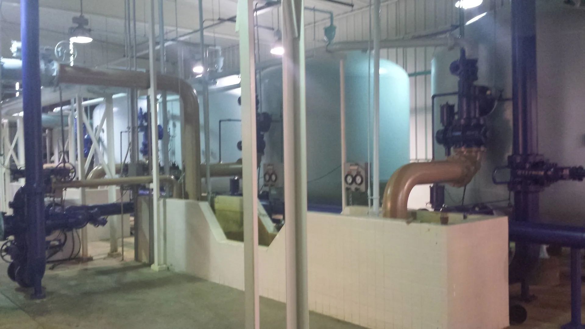 A room filled with lots of pipes and machinery in a factory.