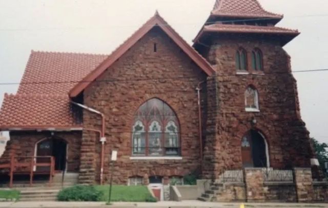A brick church with a red roof and stained glass windows