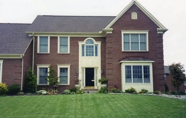 A large brick house with a lush green lawn in front of it
