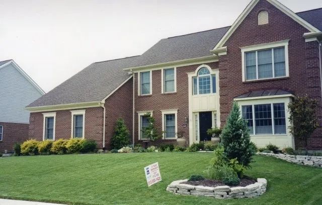 A large brick house with a for sale sign in front of it