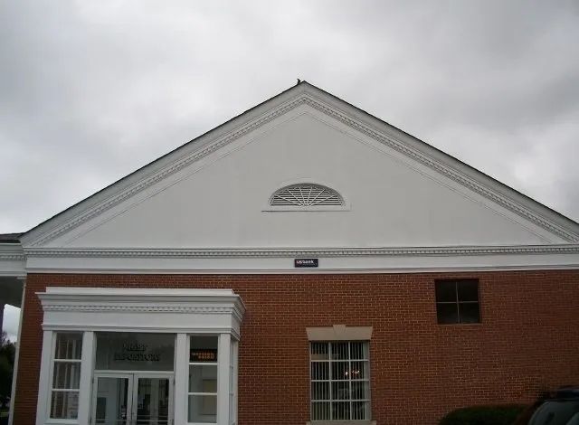 A brick building with a white roof and a car parked in front of it