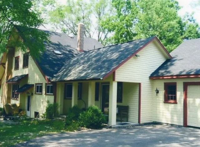 A white house with a black roof and red trim
