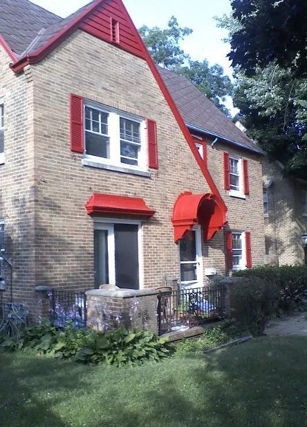 A brick house with red shutters on the windows