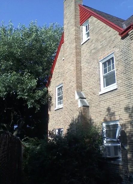 A brick house with a red roof and white windows
