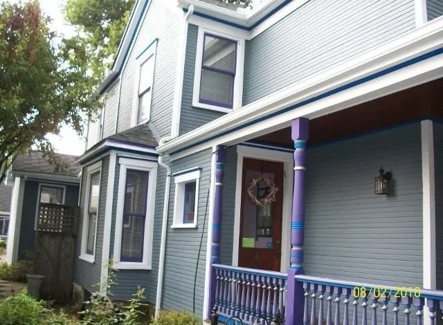 A blue and white house with a purple porch
