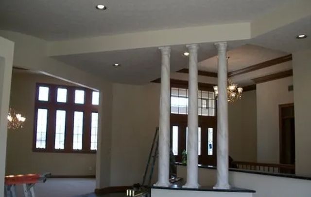 A room with columns and a staircase in the background