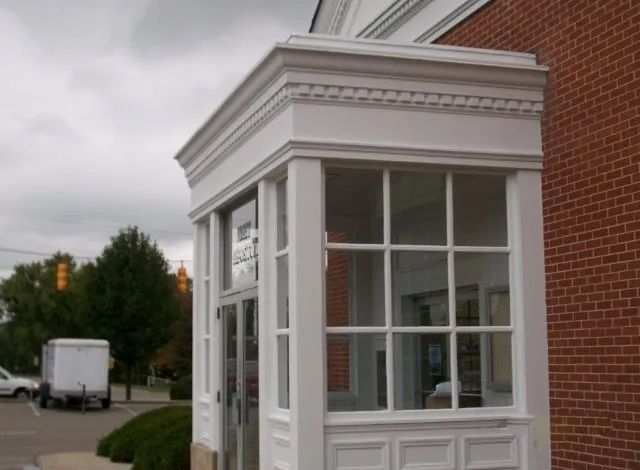 A white van is parked in front of a brick building