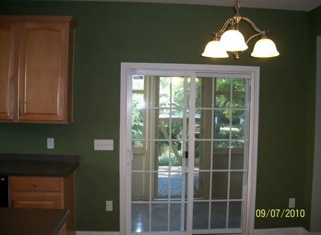 A kitchen with green walls and sliding glass doors