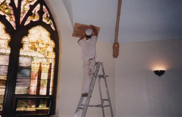 A man on a ladder in front of a stained glass window