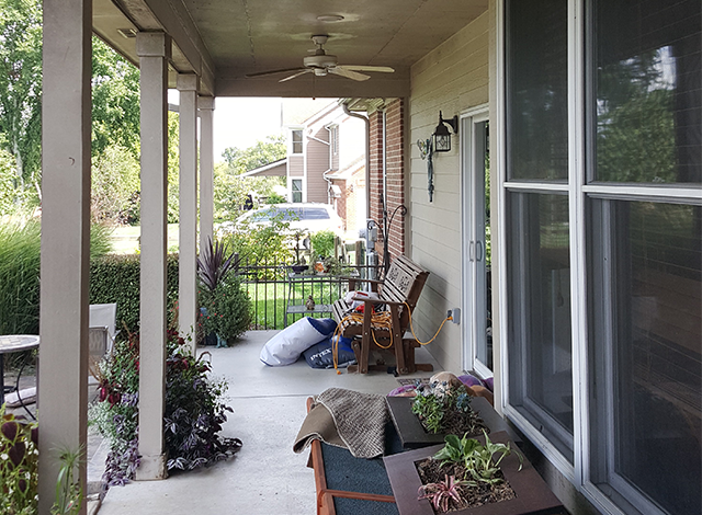 A porch with a bench and a ceiling fan
