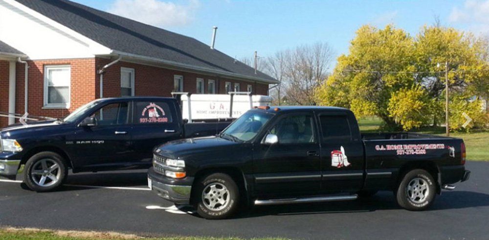 Two black trucks are parked in front of a brick building.