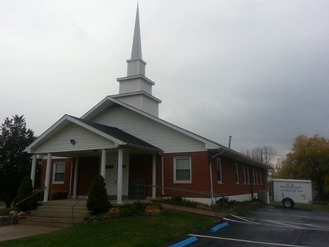 A church with a steeple and a parking lot in front of it
