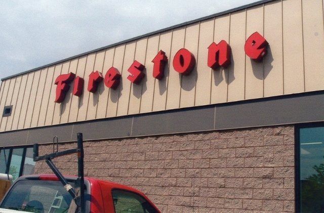 A red truck is parked in front of a firestone store