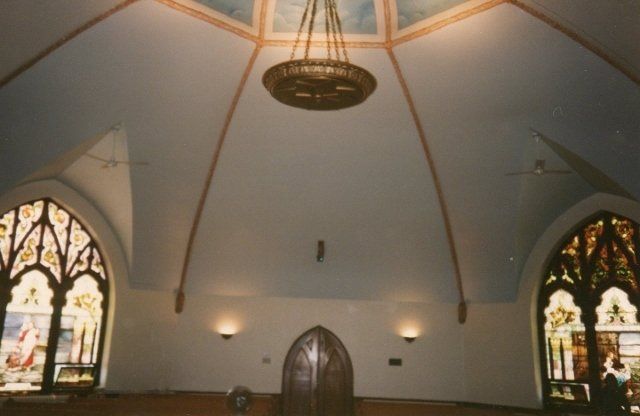 A church with stained glass windows and a chandelier hanging from the ceiling