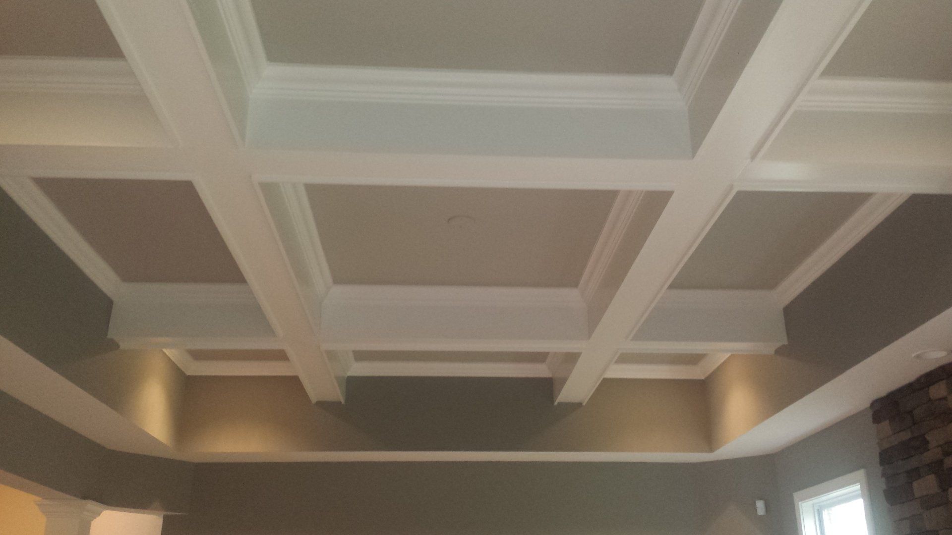 A living room with a coffered ceiling and a fireplace.