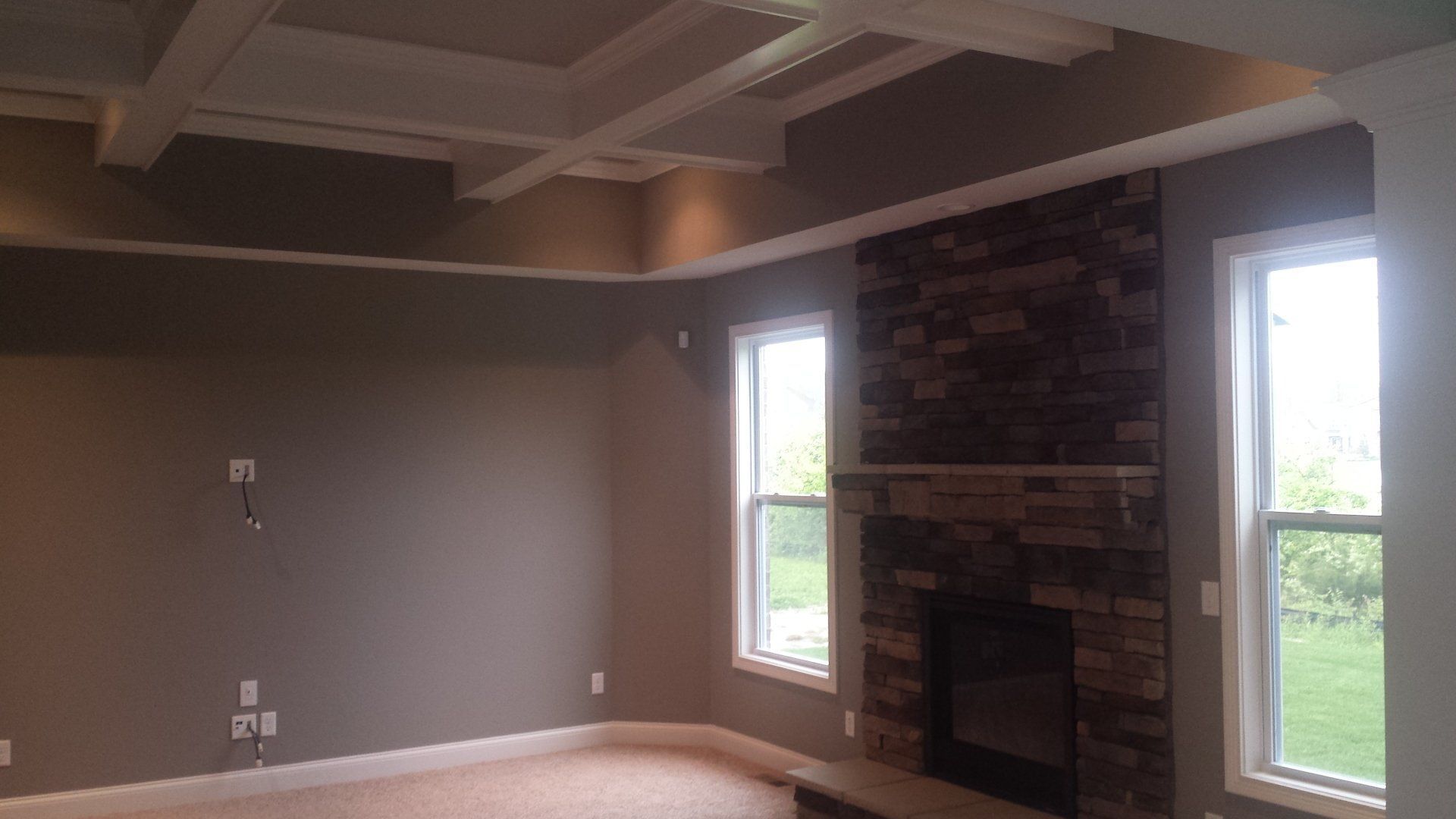 An empty living room with a fireplace and two windows.