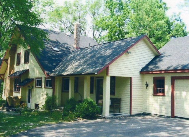 A yellow house with a black roof and red trim