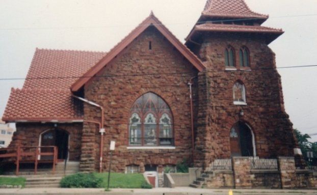 A brick church with a red roof and stained glass windows