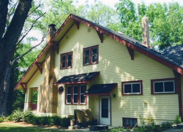 A yellow house with red trim and a chimney