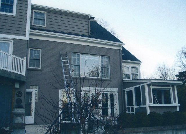 A man standing on a ladder in front of a house