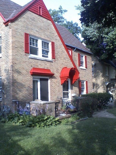 A brick house with red shutters on the windows