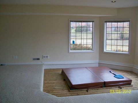 An empty room with two windows and a hot tub