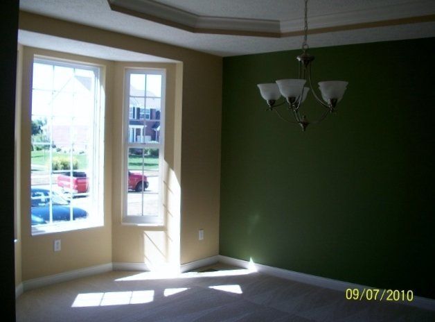 An empty room with green walls and a chandelier