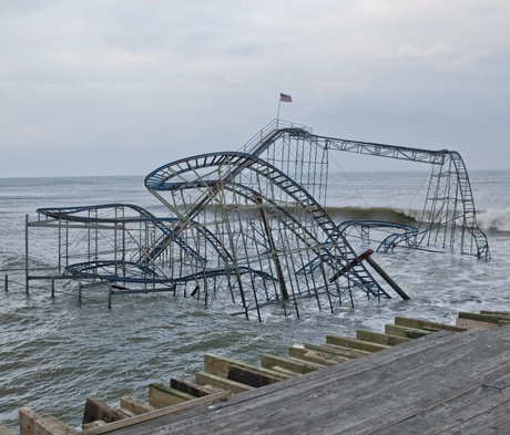 Collapsed rollercoaster in ocean water with an American flag atop.