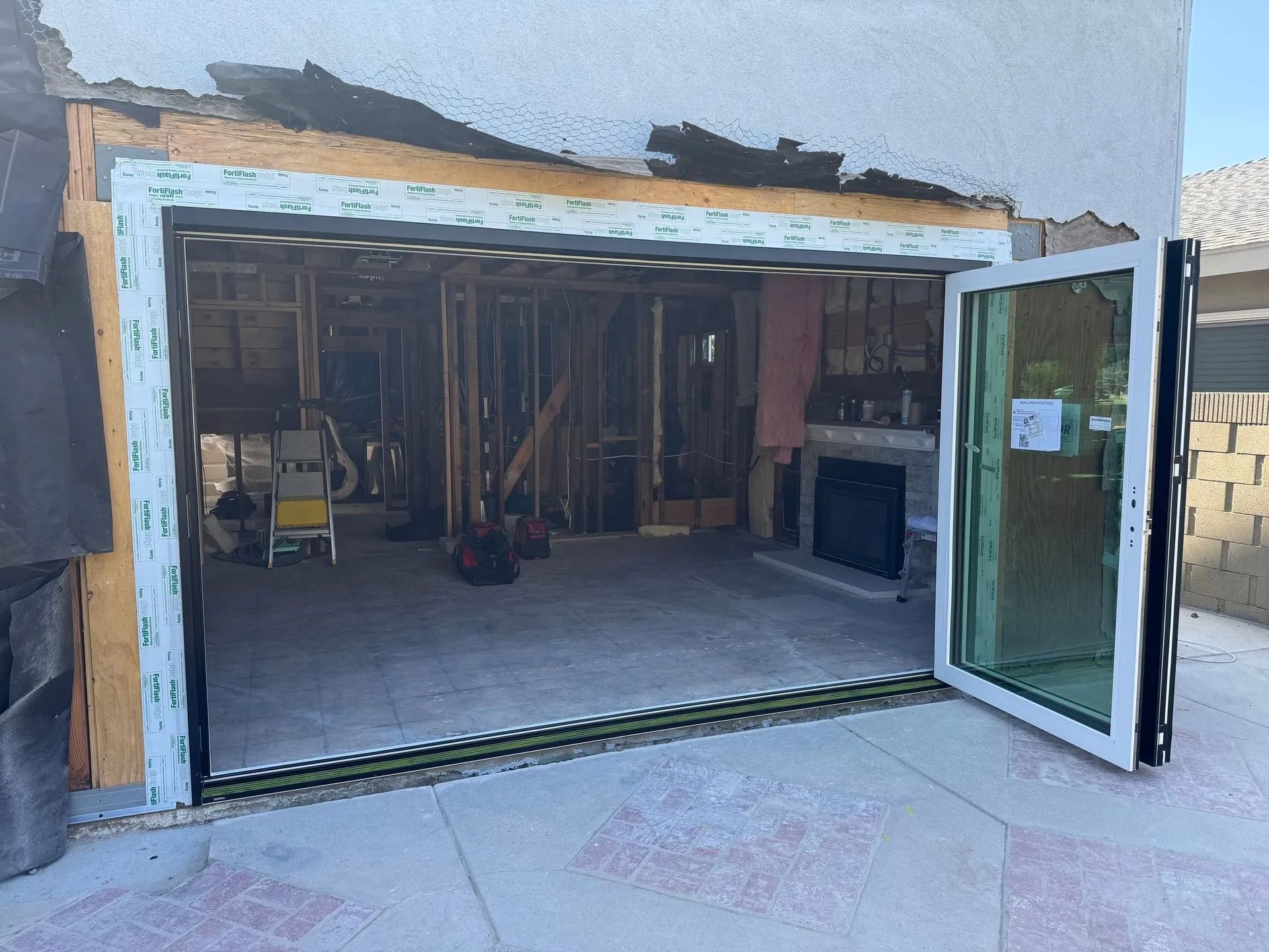 Open folding glass door revealing the interior of a house under construction.