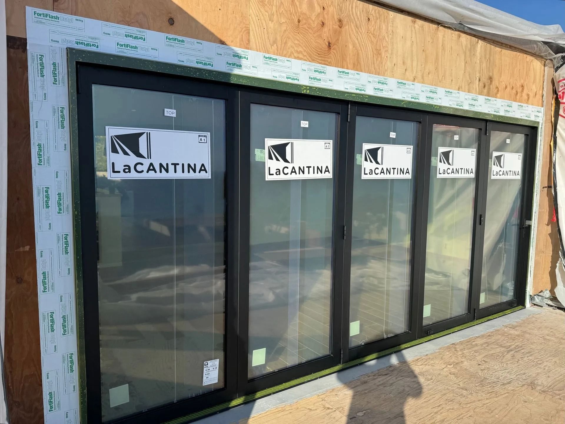 Black LaCantina folding glass door installed in a building under construction.