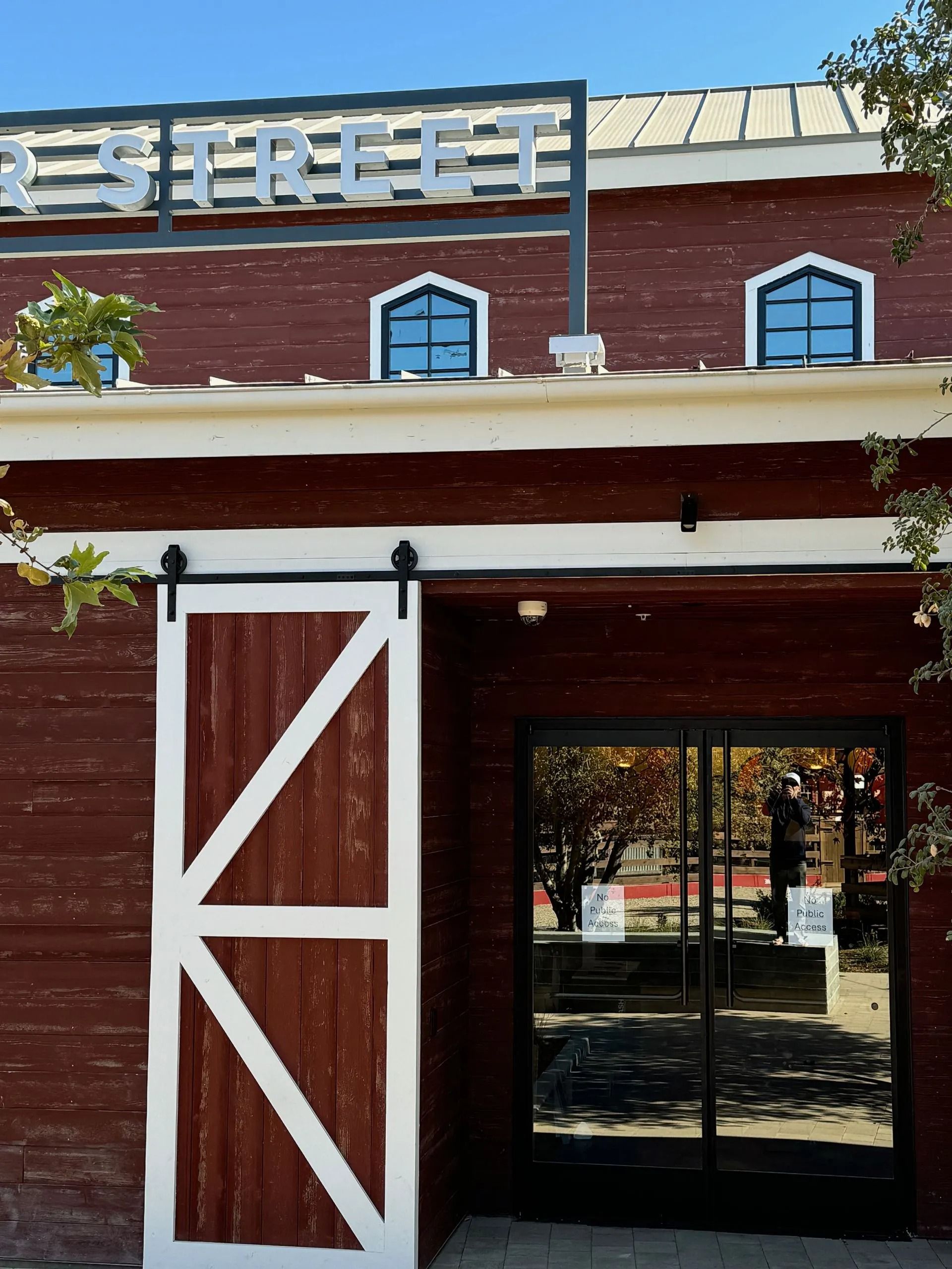 Red building with sliding barn door and glass doors, sign reads 