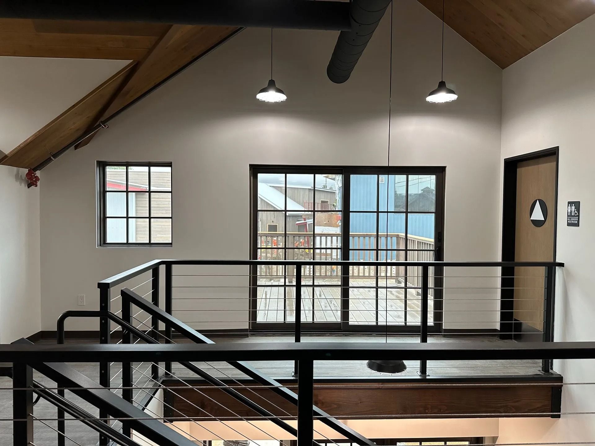 Interior loft with black railings, windows, and two hanging lights.