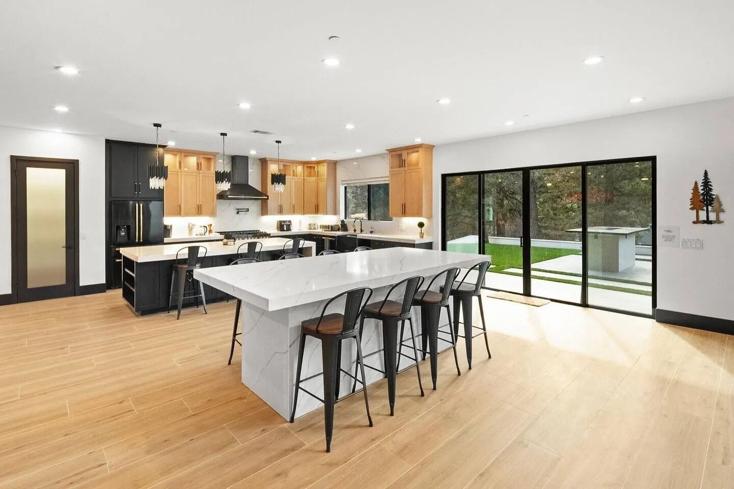 Spacious modern kitchen with light wood floors, black and light wood cabinets, and large island with seating.