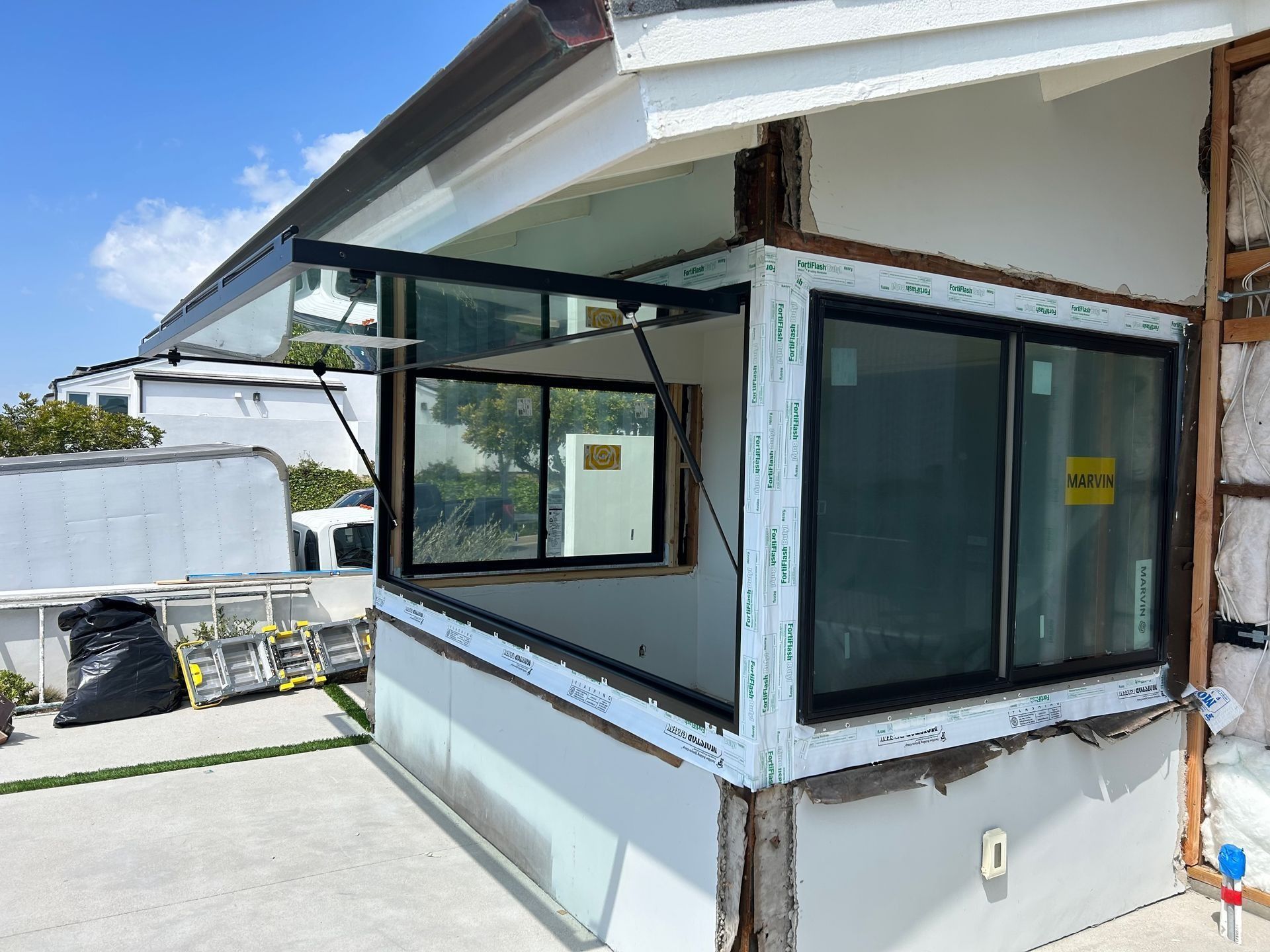 Exterior of house under construction with installed windows. Exterior walls show exposed framing.