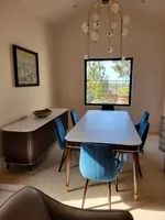Dining room with blue chairs, a table, and a sideboard. A TV is above the table.
